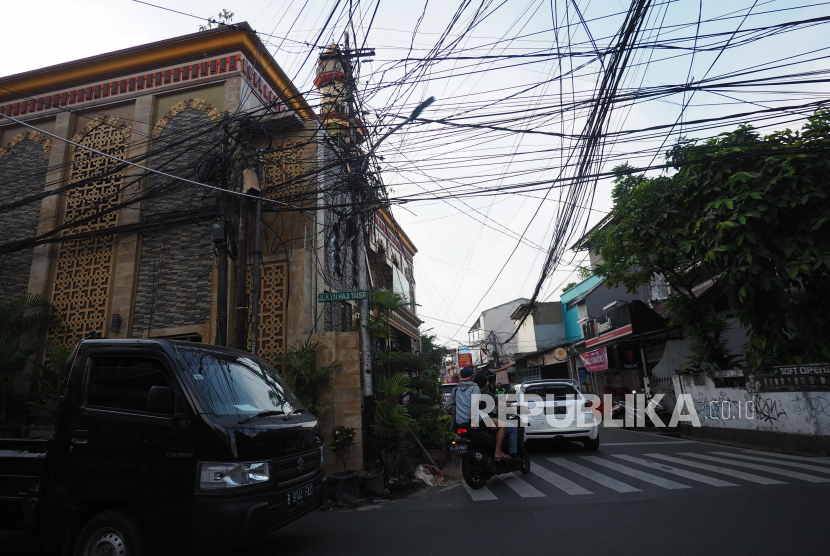 Suasana persimpangan Jl Kiai H Syahdan - Rawa Belong 2 dengan latar kabel utilitas internet yang semrawut  Jakarta Barat, Rabu (14/6/2023).