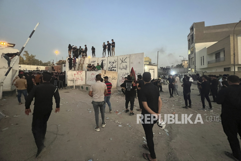 Para pengunjuk rasa memanjat tembok di Kedutaan Besar Swedia di Baghdad, Kamis (20/7/2023). Para pengunjuk rasa yang marah dengan rencana pembakaran salinan Alquran menyerbu kedutaan Kamis pagi, membobol kompleks dan menyalakan api kecil.