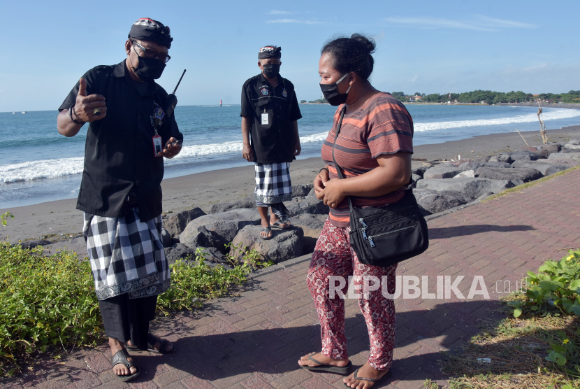 Delapan Pasien Covid-19 di Bali Dinyatakan Sembuh. Petugas keamanan desa adat atau Pecalang menegur warga yang beraktivitas di Pantai Padang Galak, Denpasar, Bali.