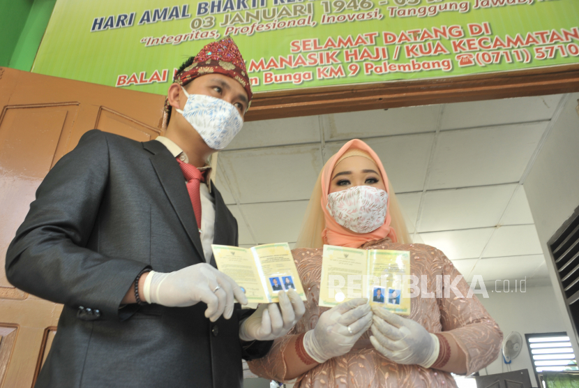 Sepasang pengantin menunjukkan buku pernikahan mereka setelah melangsungkan akad nikah di KUA Kecamatan Sukarame Palembang, Sumsel. Kemenag Sumsel belum mengizinkan masyarakat setempat melaksanakan akad nikah di rumah. Ilustrasi.