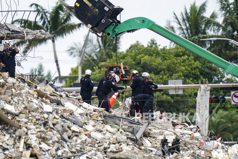 Petugas melakukan evakuasi penyelamatan di reruntuhan Apartemen Champlain Towers South, Surfside, Florida, Selasa (29/6). Pihak berwenang mencatat hingga Selasa (29/6), Korban meninggal dunia akibat runtuhnya gedung apartemen 12 lantai tersebut menjadi 12 jiwa. (AP Photo/Lynne Sladky)Putra M. Akbar