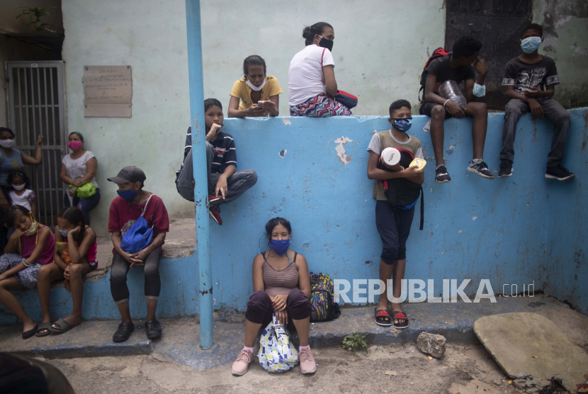 Penduduk yang memakai masker wajah sebagai tindakan pencegahan terhadap coronavirus baru menunggu di luar dapur umum untuk menerima makan siang paket-dan-pergi di lingkungan Petare di Caracas, Venezuela, Rabu, 15 Juli 2020, di tengah pandemi coronavirus baru. 