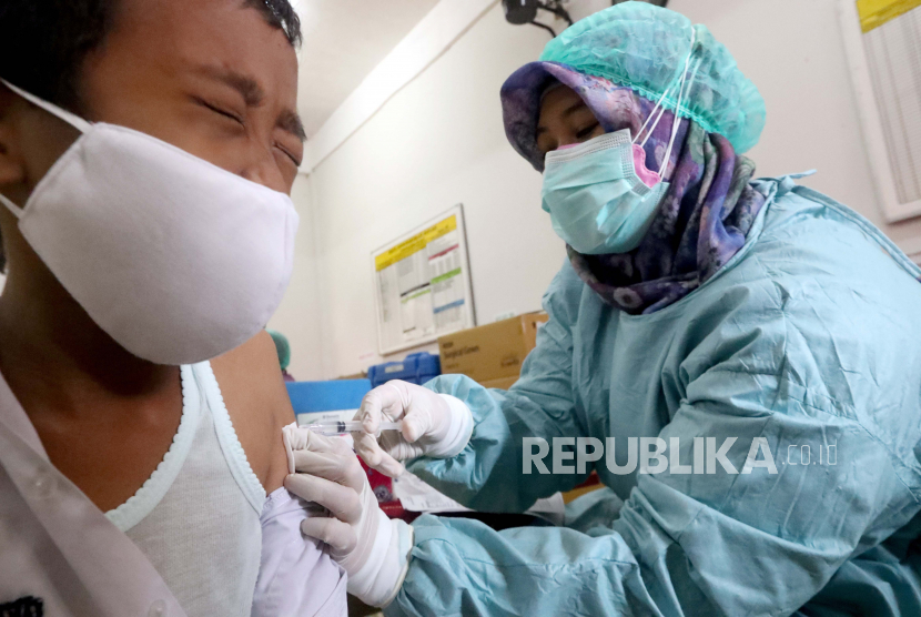  Seorang petugas kesehatan memberikan dosis vaksin COVID-19 kepada seorang siswa sekolah dasar selama perjalanan vaksinasi untuk anak-anak antara usia enam hingga 11 tahun, di sebuah sekolah dasar SDN 01 di Depok, Jawa Barat, Selasa (14/12/2021).