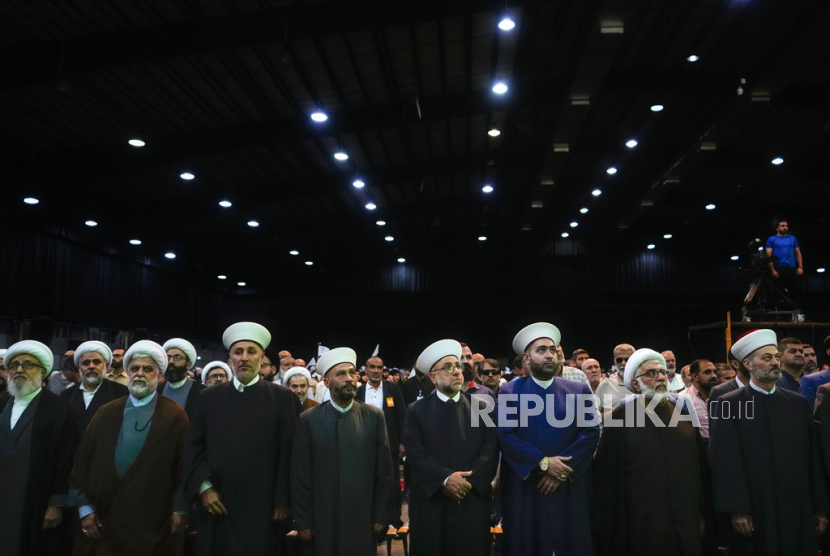 Sunni and Shiite clerics stand for the Lebanese national anthem before Hezbollah leader Sayyed Hassan Nasrallah speaks via a video link during a ceremony marking Prophet Muhammad