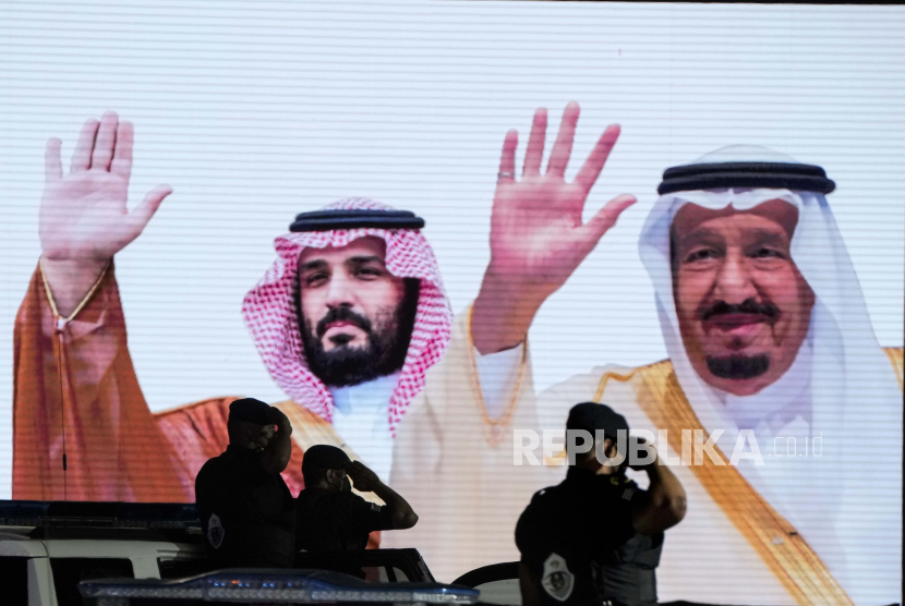  Pasukan khusus Saudi memberi hormat di depan layar yang menampilkan gambar Raja Saudi Salman, kanan, dan Putra Mahkota Mohammed bin Salman setelah parade militer dalam persiapan haji tahunan, di kota suci Muslim Mekah, Arab Saudi, Ahad, 3 Juli , 2022. Bhub