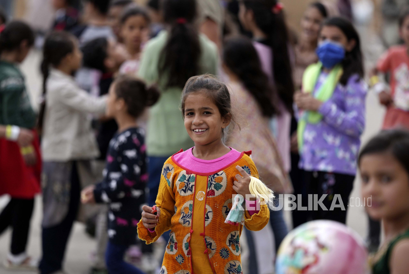 Seorang gadis muda Afghanistan yang baru saja dievakuasi tersenyum ke kamera 