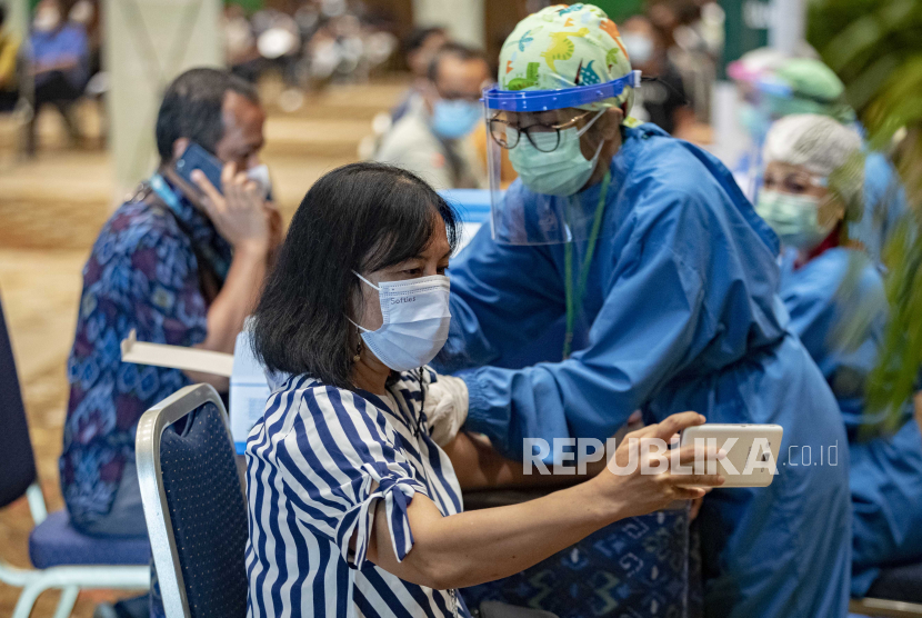  Seorang perempuan menerima suntikan vaksin COVID-19 saat program vaksinasi untuk pekerja pariwisata dan pengemudi angkutan umum di pusat vaksinasi di Nusadua, Bali, Indonesia, 03 Maret 2021.