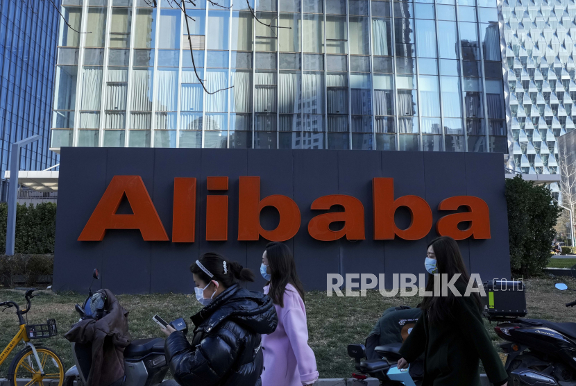  Wanita mengenakan masker berjalan melewati kantor perusahaan e-commerce China Alibaba di Beijing, Senin, 13 Desember 2021. 