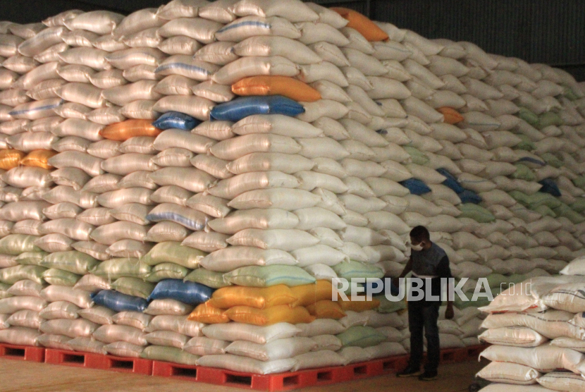 Seorang pria berjalan di dekat tumpukan karung berisi beras di gudang Bulog wilayah NTT di Kupang, NTT, Senin (18/5)