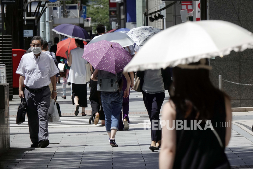  Orang-orang menggunakan payung di bawah terik matahari. Jepang Minta Warga Hemat Energi di Tengah Gelombang Panas Tokyo
