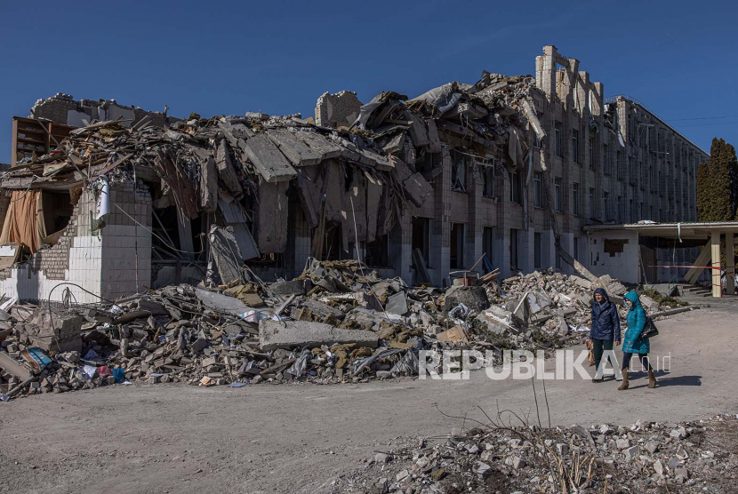 Orang-orang berjalan melewati sebuah sekolah yang rusak parah setelah penembakan Rusia, di kota Zhytomyr, barat laut Ukraina, 20 Maret 2022.