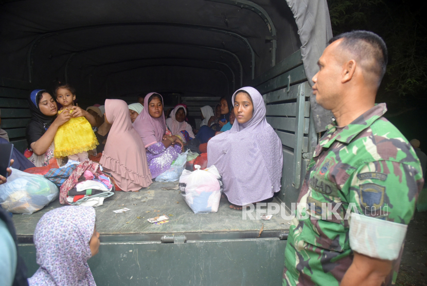 Seorang perwira militer berdiri di samping truk yang membawa pengungsi Rohingya, termasuk perempuan dan anak-anak, di tempat penampungan sementara di Pidie, Provinsi Aceh, Indonesia, 27 Desember 2022. Polisi setempat mengatakan bahwa 174 migran etnis Rohingya mendarat di Pantai Laweung Pidie, Provinsi Aceh di Indonesia pada 26 Desember, setelah dikabarkan berlayar selama berminggu-minggu di laut. Menurut pernyataan yang dikeluarkan pada 27 Desember oleh Badan Pengungsi PBB (UNHCR), lebih dari 200 orang dibawa ke pantai dengan aman di barat laut Indonesia selama beberapa hari terakhir. Dua kelompok, sekitar 58 pada 25 Desember, dan 174, termasuk mayoritas wanita dan anak-anak, pada 26 Desember, diselamatkan dan diturunkan oleh nelayan Indonesia dan pihak berwenang setempat, tambah UNHCR.