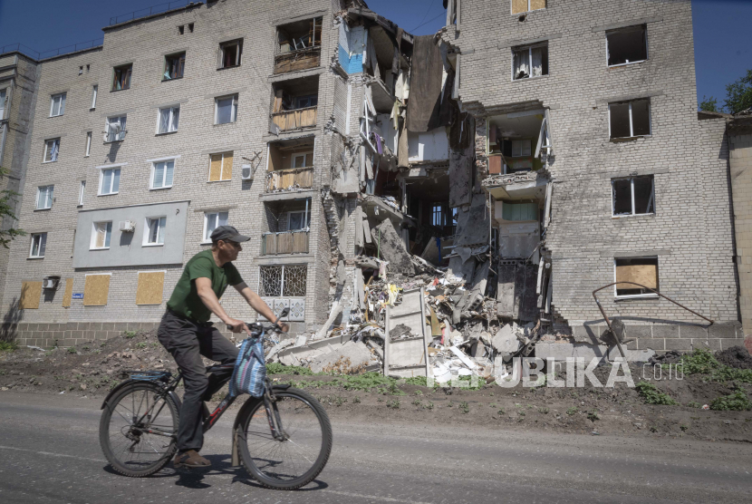 Seorang pria mengendarai sepeda melewati sebuah bangunan yang rusak dalam penembakan Rusia di Bakhmut, wilayah Donetsk, Ukraina, Senin, 20 Juni 2022. Ukraina Evakuasi 3.000 Warganya dari Donetsk