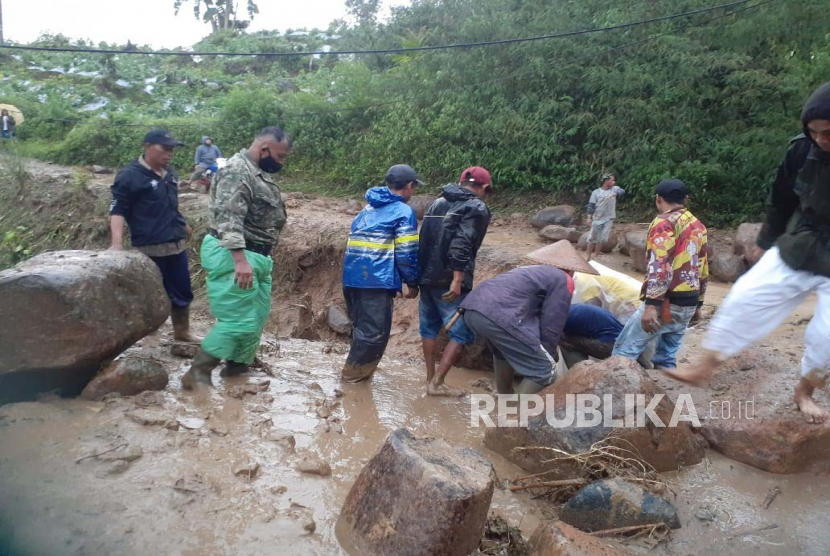 Warga beserta aparat setempat membersihkan material yang terbawa banjir dan menutup jalan di Desa Mekarmulya, Kecamatan Talegong, Kabupaten Garut, Jawa Barat, Rabu (29/3/2023). 