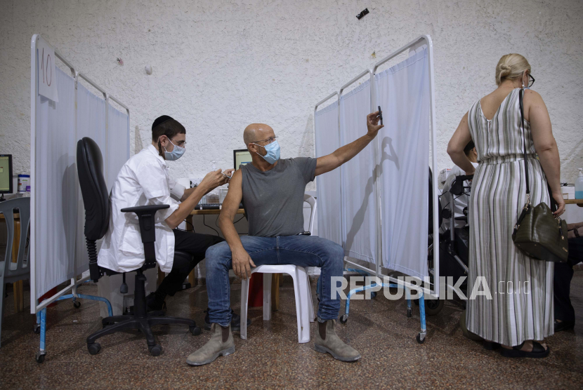 Seorang pria Israel mengambil selfie saat menerima vaksin Pfizer-BioNTech COVID-19 ketiga dari staf medis di pusat vaksinasi virus corona di Ramat Gan, Israel, Senin, 30 Agustus 2021. 