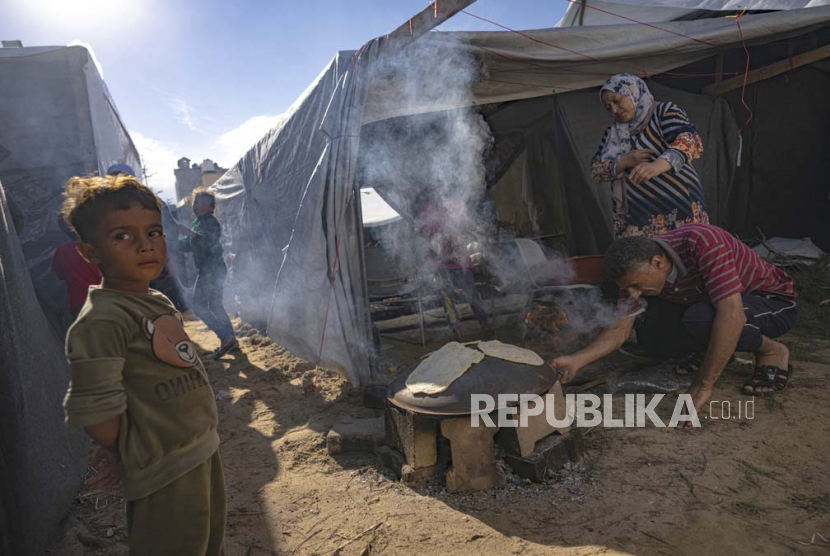 Warga Palestina yang mengungsi akibat pemboman Israel di Jalur Gaza menyiapkan roti di tenda kamp yang disediakan UNDP di Khan Younis, Rabu, 15 November 2023.
