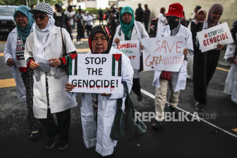 Dokter Malaysia dan anggota organisasi non-pemerintah (LSM) memegang plakat saat Rapat Umum Jas Putih di luar kedutaan Mesir di Malaysia sebagai bentuk solidaritas dengan dokter di Gaza, 16 November 2