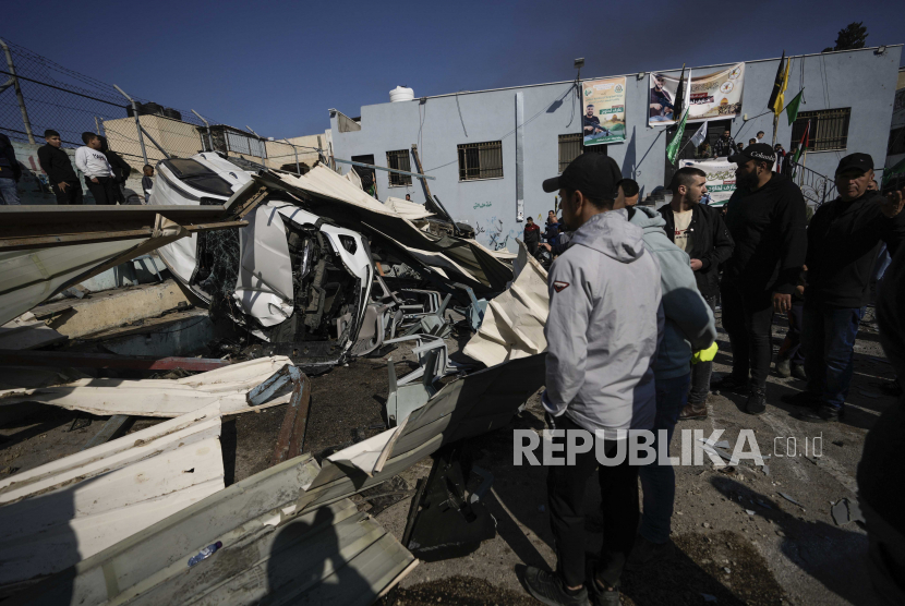 Warga melihat lokasi bangunan yang rusak setelah serangan pasukan Israel di kota Jenin, Tepi Barat, Kamis, (26/1/2023). Pasukan Israel menewaskan sembilan warga Palestina, termasuk seorang wanita berusia 60 tahun, dan melukai beberapa orang. (AP Photo/Majdi Mohammed)