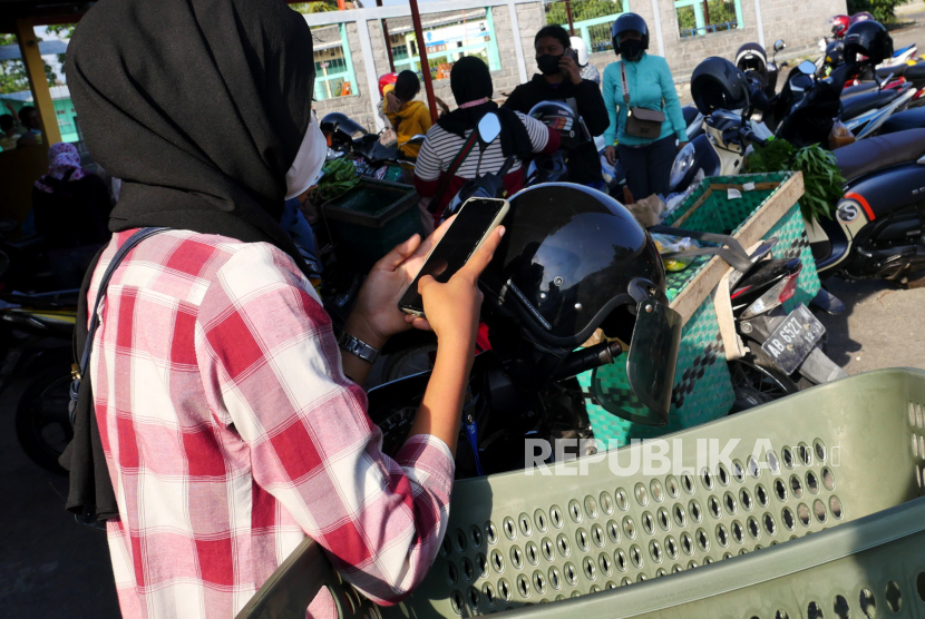 Pedagang berkomunikasi dengan gawai untuk mengambil pesanan di Pasar COD Wonosari, Gunungkidul, Yogyakarta, Selasa (7/9). Pasar COD Wonosari tercipta imbas pandemi Covid-19. Di sini tempat bertemunya pemasok dan pedagang yang sudah memesan barang melalui grup WhatsApp atau telegram. Pemasok datang hanya membawa pesanan barang pedagang, selanjutnya pedagang yang mengantarkan ke rumah pelanggan. Pasar ini hanya berlangsung dari pukul 15.00 hingga pukul 17.00. Barang yang dijual beragam mulai bahan makanan hingga perlengkapan rumah tangga. Dan mayoritas yang menjadi pelaku ada perempuan.