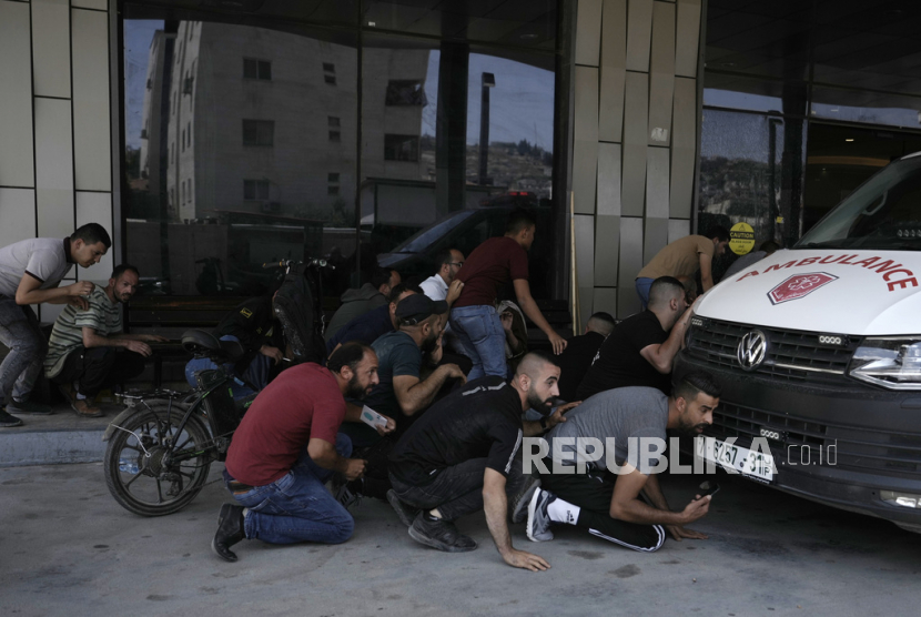Warga Palestina berlindung saat penyerbuan pasukan di luar sebuah rumah sakit di kota Jenin, Tepi Barat, Senin, (19/6/2023).