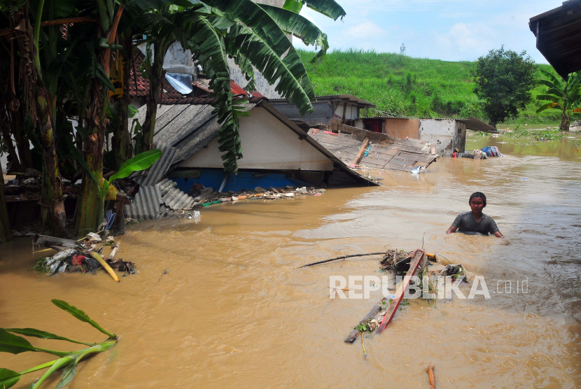 Seorang anak menerobos banjir di samping rumah yang roboh di Desa Gubug, Gubug, Grobogan, Jawa Tengah, (ilustrasi)