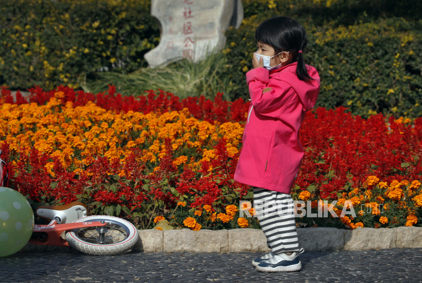  Seorang anak memegang masker wajahnya untuk membantu mengekang penyebaran permainan virus korona di sebuah taman di Beijing, Kamis (5/11). China melaporkan 20 kasus Covid-19 baru pada Jumat (25/12). Otoritas kesehatan pada Sabtu (24/12) menyebutkan, jumlah ini meningkat dibandingkan hari sebelumnya yang 14 kasus.