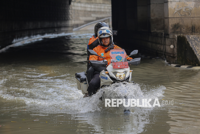 Petugas Dinas Perhubungan menerobos banjir untuk mengecek ketinggian air yang menggenangi area Underpass Mampang, Jakarta, Ahad (8/3/2026). Banjir setinggi sekitar 30-70 centimeter tersebut terjadi sejak pagi hari usai diguyur hujan deras pada Ahad (8/3) dinihari. Menurut petugas, genangan tersebut terjadi lantaran pembuangan drainase yang mengalir hingga ke Kali Krukut meluap. Akibat banjir tersebut, akses jalan Underpass Mampang terpaksa ditutup sementara.