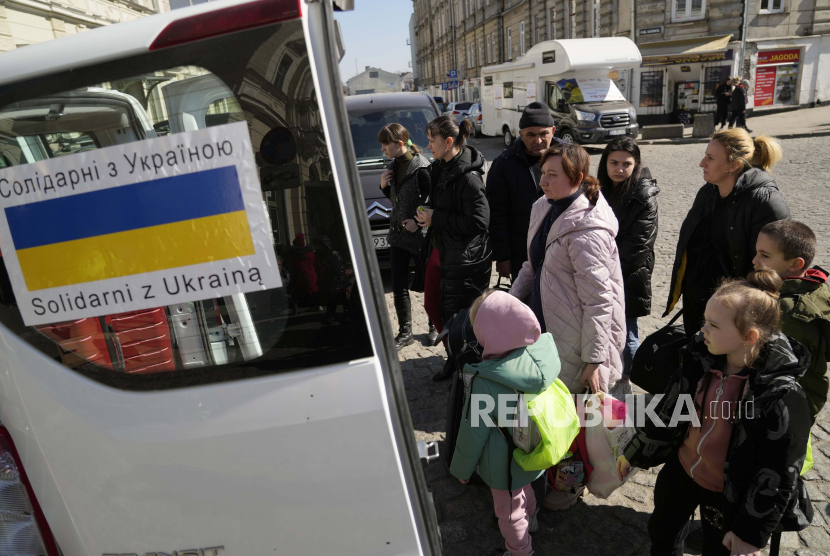Pengungsi Ukraina dengan anak-anak menaiki transportasi di alun-alun di sebelah stasiun kereta api di Przemysl, Polandia, pada Selasa, 22 Maret 2022. Polandia telah mengusir 45 diplomat Rusia.
