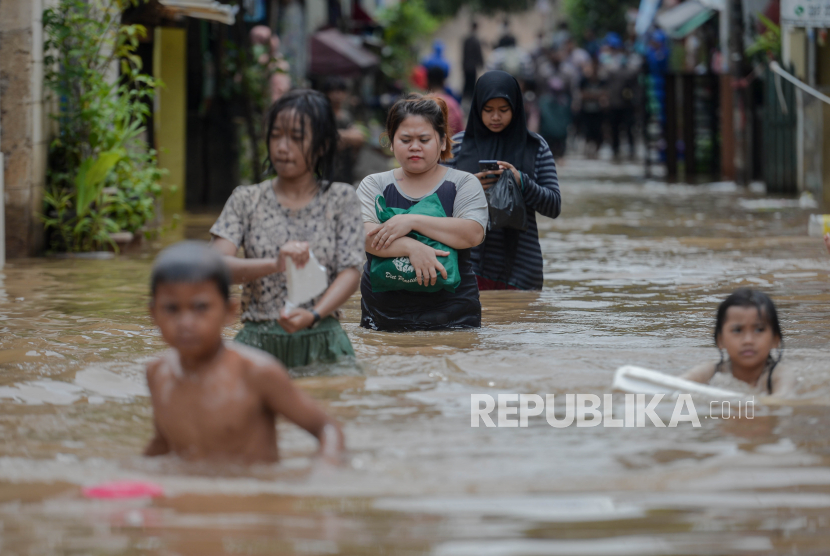 Warga berjalan melintasi banjir yang merendam kawasan Cipinang Melayu, Jakarta Timur, Jumat (19/2). Banjir yang terjadi akibat  luapan Kali Sunter tersebut menggenangi sebanyak lima Rukun tetangga diantaranya RT 01 hingga RT 05 yang bread di RW 04 dengan ketinggian 90 centimeter.