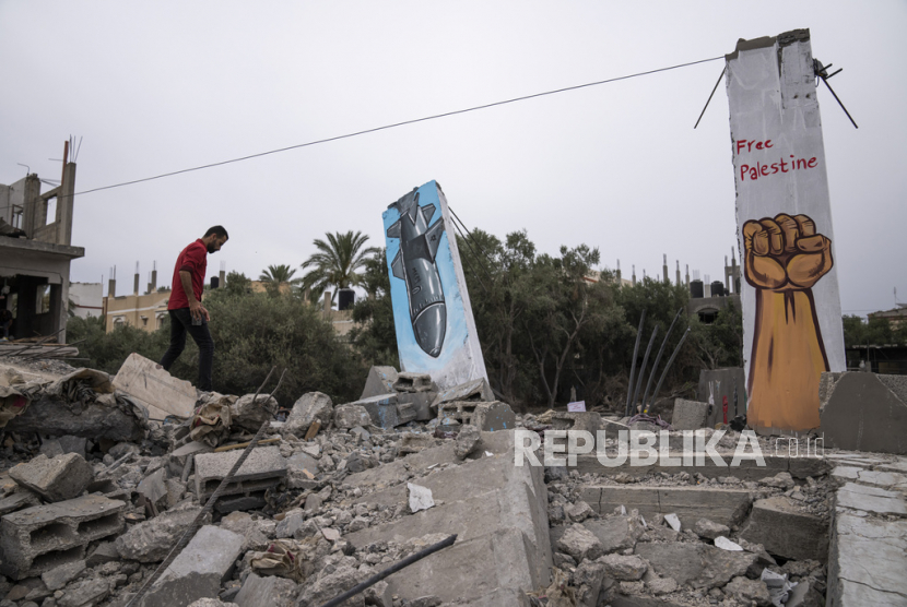Seorang pria Palestina berjalan melewati mural yang dilukis di atas puing-puing sebuah rumah yang hancur dalam serangan Israel di Deir al-Balah, Jalur Gaza tengah, Kamis, (8/6/ 2023).