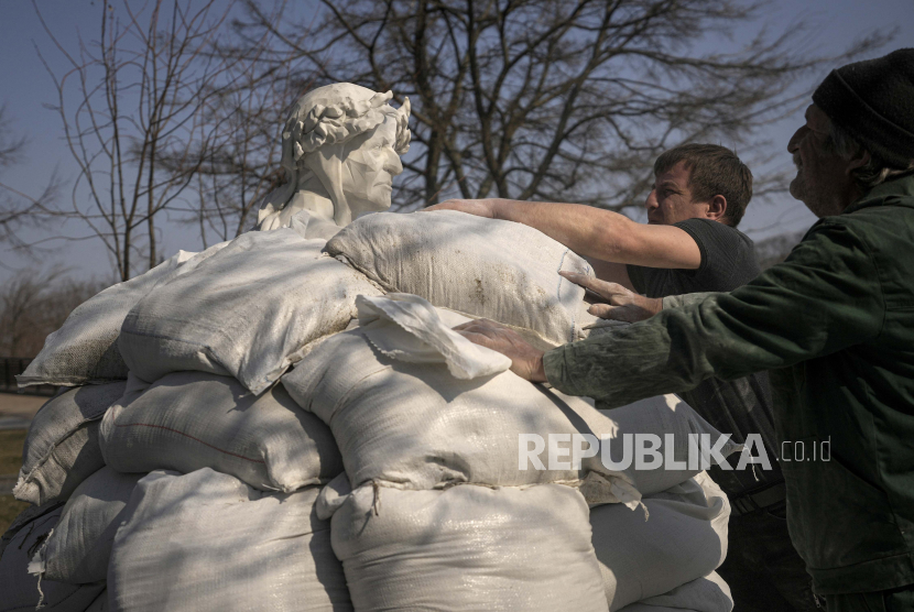 Pekerja kota selesai menutupi patung penyair dan filsuf Italia Dante Alighieri dengan karung pasir untuk melindunginya dari potensi kerusakan akibat penembakan, di Kyiv, Ukraina, Rabu, 23 Maret 2022.
