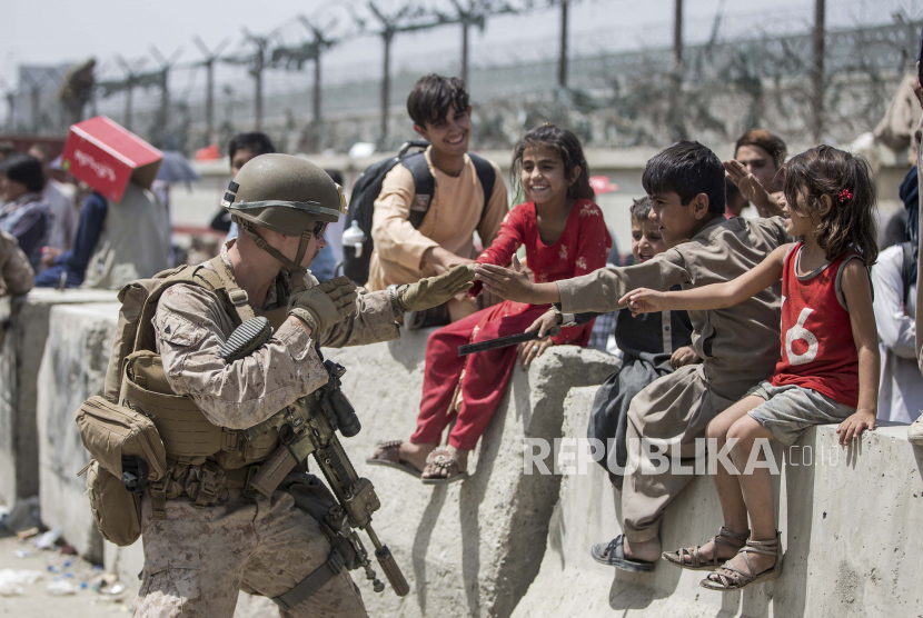 Dalam gambar yang disediakan oleh Korps Marinir AS ini, seorang Marinir dengan Satuan Tugas Udara-Tanah Laut Tujuan Khusus-Komando Pusat Respons Krisis (SPMAGTF-CR-CC) bermain dengan anak-anak yang menunggu untuk diproses selama evakuasi di Bandara Internasional Hamid Karzai di Kabul , Afghanistan, Jumat, 20 Agustus 2021. AS resmi mengizinkan pemerintah AS dan PBB untuk berbisnis dengan Taliban.