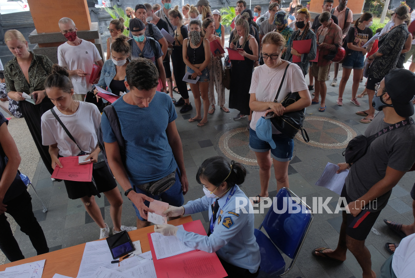 Petugas imigrasi memeriksa dokumen warga negara asing (WNA) saat mereka antre mengurus perpanjangan visa dan permohonan izin tinggal di Kantor Imigrasi Kelas I Khusus Ngurah Rai, Badung, Bali, Senin (23/3/2020).
