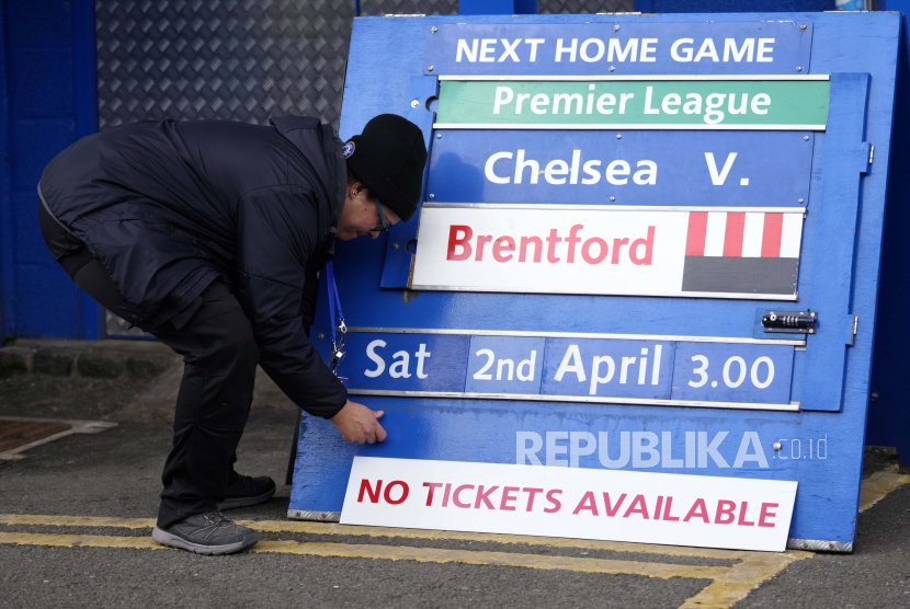 Seorang anggota staf lapangan menyesuaikan papan pertandingan yang akan datang menjelang pertandingan sepak bola Liga Premier Inggris antara Chelsea dan Newcastle United di stadion Stamford Bridge di London, Ahad, 13 Maret 2022.