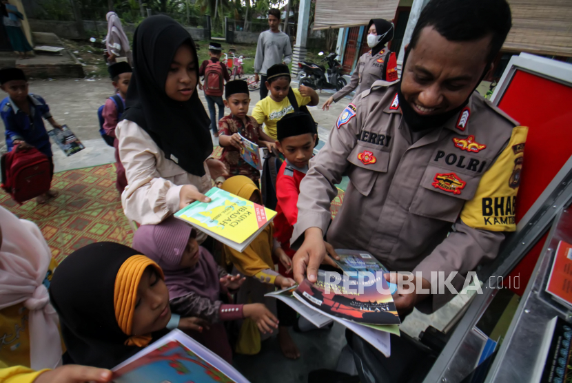 Polisi membagikan buku bacaan untuk anak-anak saat kegiatan Polisi Mengajar di sebuah desa. (ilustrasi)