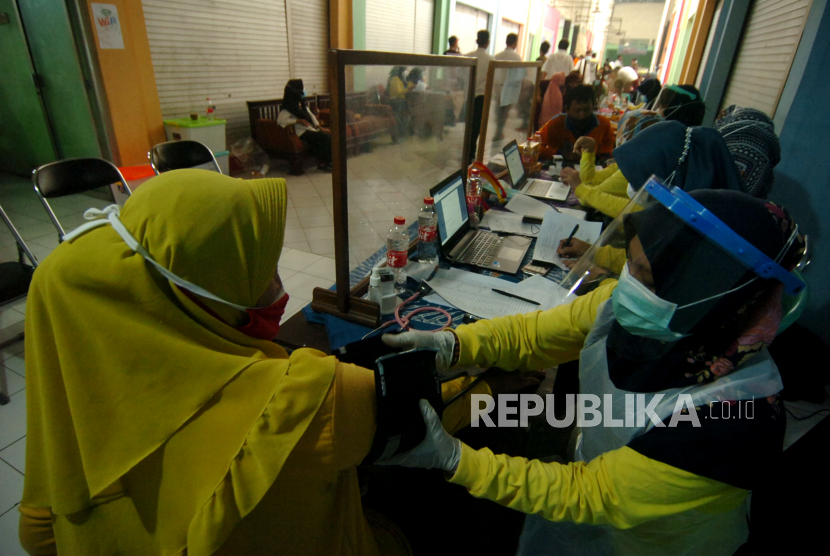 Petugas medis memeriksa kesehatan pedagang pasar sebelum melakukan vaksinasi (ilustrasi)