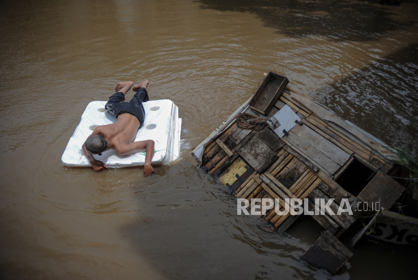 Seorang warga menggunakan styrofoam di permukiman yang terendam banjir, di Kelurahan Utama, Kecamatan Cimahi Selatan, Kota Cimahi, Jawa Barat, Senin (8/2/2021). Banjir setinggi 30 hingga 80 sentimeter akibat luapan Sungai Cihujung tersebut merendam puluhan rumah dan akses jalan dari Kota Cimahi menuju Kabupaten Bandung. 