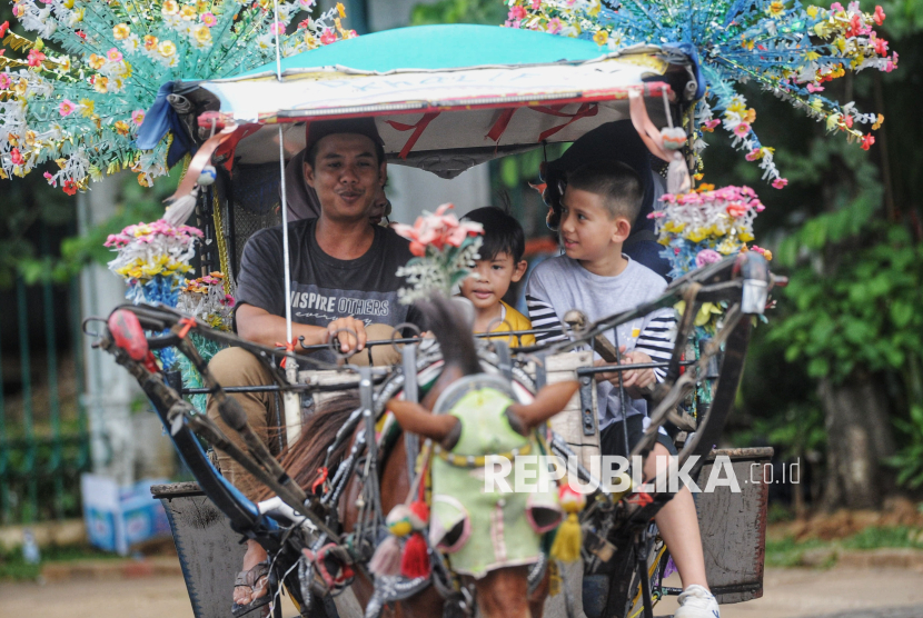 Wisatawan berkeliling dengan delman di area luar Monumen Nasional (Monas) di Jakarta, Sabtu (28/12/2024). Momen libur sekolah dan nataru seperti ini menjadi berkah tersendiri bagi para kusir delman wisata di Monas.