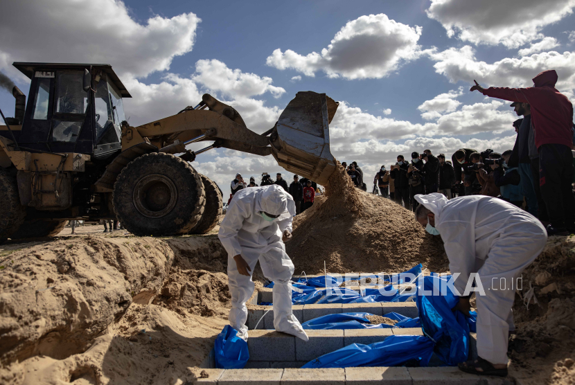 Petugas Kementerian Kesehatan Palestina mempersiapkan jenazah untuk pemakaman massal di kamp Rafah, selatan Jalur Gaza, Selasa (30/1/2024).