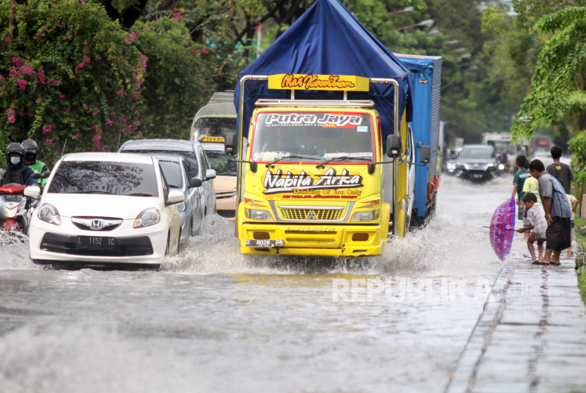 Kendaraan menerobos banjir di Jalan Raya Juanda, Sidoarjo, Jawa Timur, Senin (28/6/2021). Hujan yang turun dengan intensitas cukup tinggi sejak Minggu (27/6)  menyebabkan aktivitas transportasi di kawasan bandara juanda tergenang banjir dengan ketinggian 20-40 cm. 