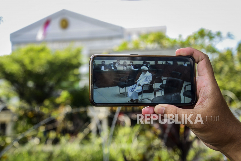 Layar telepon genggam yang memperlihatkan Habib Rizieq Shihab saat menjalani sidang putusan kasus kerumunan di Pengadilan Negeri Jakarta Timur, Kamis (27/5). 