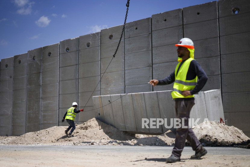 Para pekerja menempatkan bagian dari dinding beton setinggi sembilan meter (30 kaki) untuk menggantikan pagar perbatasan antara Tepi Barat utara dan Israel, dekat desa Arab Salem, Rabu, 22 Juni 2022. Israel menduduki peringkat kelima sebagai negara terburuk di dunia untuk bekerja.