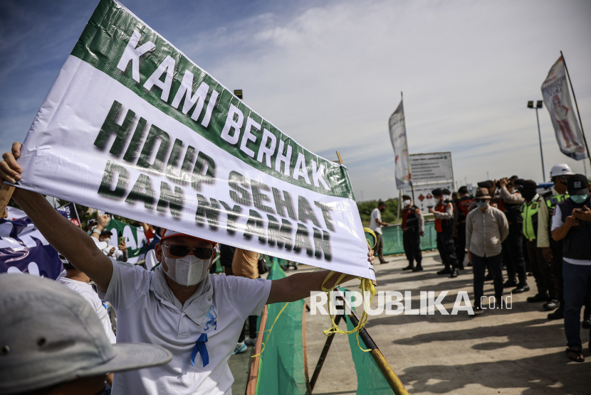 Warga membentangkan spanduk saat mengikuti unjuk rasa di depan kawasan Refuse Derived Fuel (RDF) Plant, Rorotan, Jakarta Utara, Jumat (21/3/2025). Dalam aksinya mereka menuntut untuk RDF Plant tersebut ditutup karena telah mencemari udara di lingkungan sekitar. 