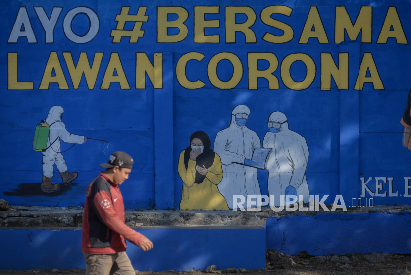Korlantas Polri menempelkan stiker kampaye pakai masker ungtuk cegah penularan Covid-19. Foto, warga tidak menggunakan masker dengan benar saat berjalan melintasi mural bertema Covid-19 di kawasan Bukit Duri, Tebet, Jakarta Selatan. (ilustrasi)