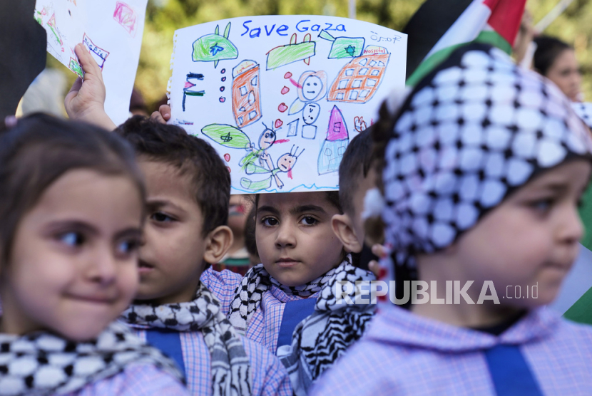 Seorang siswa SD Palestina memegang plakat, saat ia bersama siswa lainnya menghadiri aksi duduk di luar kantor Delegasi Uni Eropa untuk Lebanon, untuk menunjukkan solidaritas mereka terhadap rakyat Palestina di Gaza, di Beirut, Lebanon, Kamis, (14/12/2023).