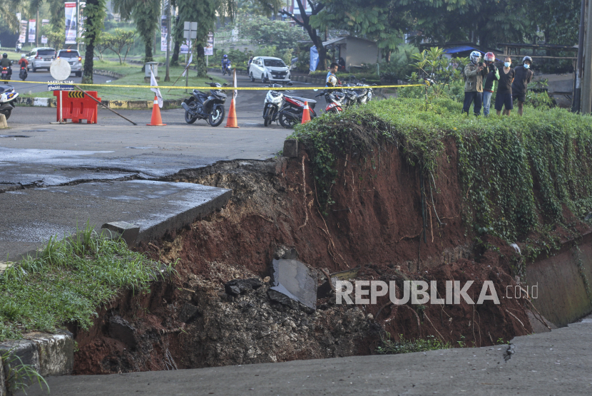 Sejumlah warga melihat jalan yang longsor di Jalan Raya Boulevard, GDC, Depok, Jawa Barat, Selasa (13/4/2021). Longsor yang terjadi pada Senin (12/4) pukul 21.00 WIB tersebut akibat intensitas hujan yang tinggi  dan menyebabkan sebagain jalan amblas dengan kedalaman dan lebar kurang lebih 5 meter. 