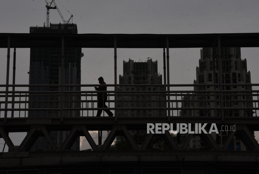 Pekerja berjalan di atas JPO Dukuh Atas, Jakarta, Senin (4/5). PT Semen Indonesia (Persero) Tbk (SIG) mengumumkan kinerja keuangan perseroan periode Januari hingga Juni 2020 atau semester I 2020. 