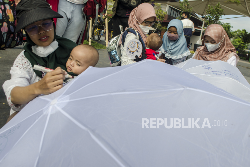 Peserta dari Asosiasi Ibu Menyusui Indonesia (AIMI) Jabar menulis aspirasi pada payung putih saat Aksi Payung AspirASI di Bandung, Jawa Barat, Ahad (7/8/2022). Aksi memperingati pekan menyusui sedunia 2022 tersebut untuk menyampaikan edukasi, peran dan dukungan seluruh masyarakat dalam menyukseskan program pemberian ASI eksklusif sesuai aturan UU No.36 Tahun 2009 tentang  kesehatan. 