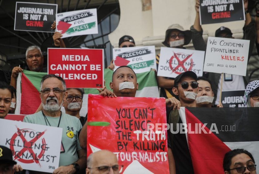 Jurnalis Malaysia memegang poster selama protes solidaritas dengan anggota pers Gaza. 