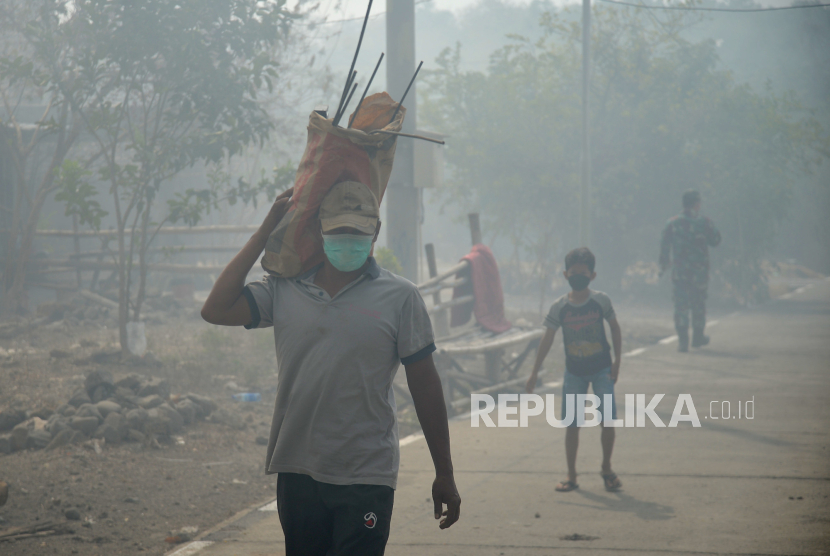 Warga beraktifitas menggunakan masker akibat pekatnya asap di Dusun Jatirejo, Mojosongo, Surakarta, Jawa Tengah, Ahad (17/9/2023). RT 3 Dusun Jatirejo menjadi daerah yang terdampak langsung imbas kebakaran TPA Putri Cempo. Warga beraktifitas memilih menggunakan masker untuk meminimalkan risiko ISPA. Untuk warga balita sudah diungsikan sejak Sabtu (16/9/2023) sore, tenaga kesehatan juga sudah turun untuk memeriksa serta memberikan obat-obatan yang diperlukan. Dusun ini lokasinya persis bersebelahan dengan TPA dan arah angin menuju ke sini.